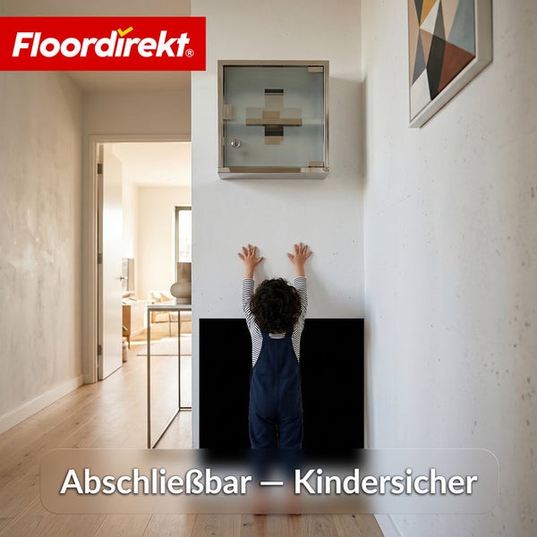 Kindersicherer, abschließbarer Erste-Hilfe-Schrank aus Edelstahl, hoch an einer Wand in einem hellen Flur montiert. Floordirekt Logo.