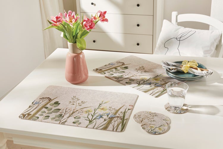 Gedeckter Esstisch mit Blumen, Platzsets und Geschirr für eine festliche Atmosphäre