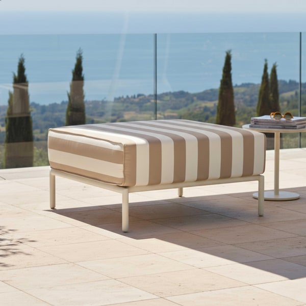 Gestreifter Outdoor-Hocker mit Metallgestell auf einer hellen Terrasse mit Blick auf das Meer und Zypressen.
