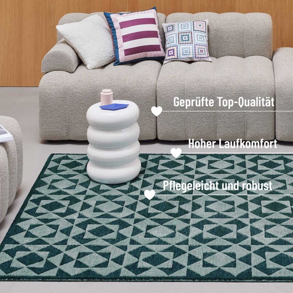 Heller, organisierter Wohnraum mit grünem geometrischem Teppich, beigem Sofa mit Kissen und weißem rundem Beistelltisch.