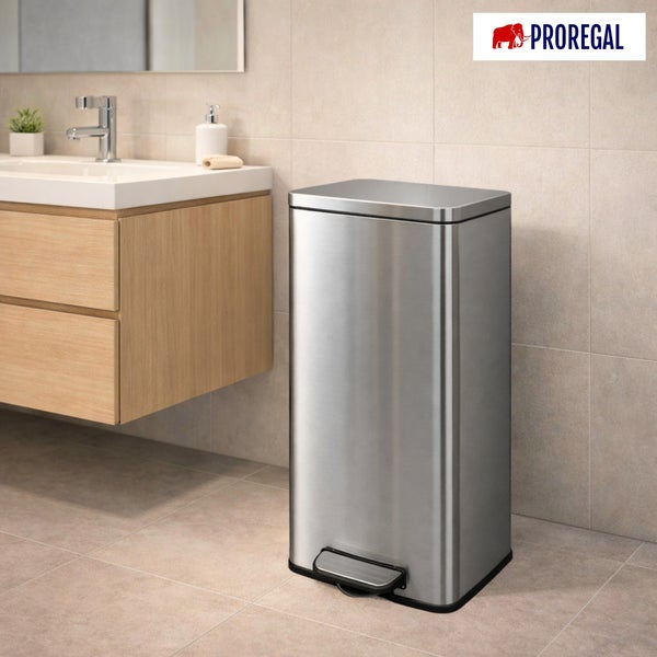 Rechteckiger Treteimer aus Edelstahl in einem hellen Badezimmer mit Waschtisch in Holzoptik und beigen Fliesen. PROREGAL Logo.