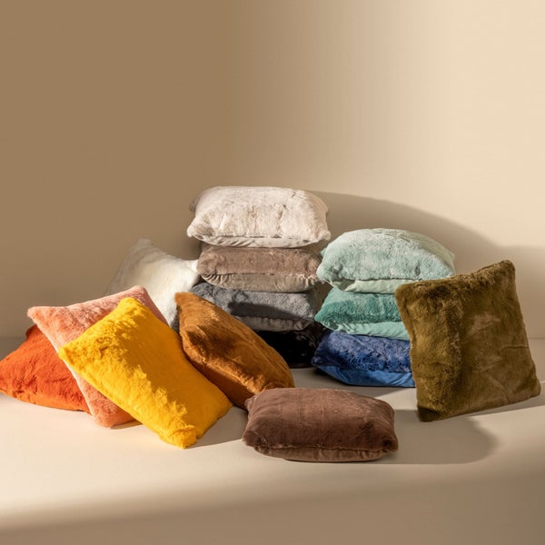 Stapel dekorativer Kissen aus Kunstfell in verschiedenen Farben