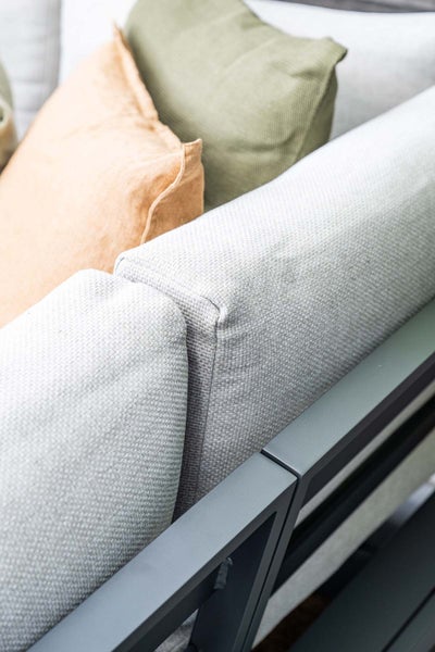 Detailansicht von hellgrauen Loungekissen mit strukturierter Oberfläche aus Textil auf einem dunklen Metallgestell für Gartenmöbel.