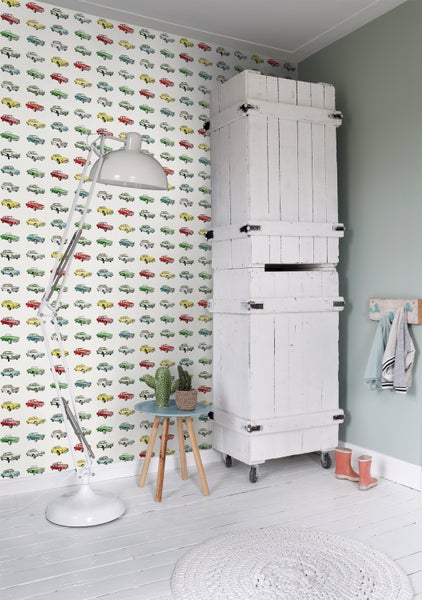 Helles Kinderzimmer mit Auto-Tapete, weißem Schrank, Stehlampe und kleinem Tisch