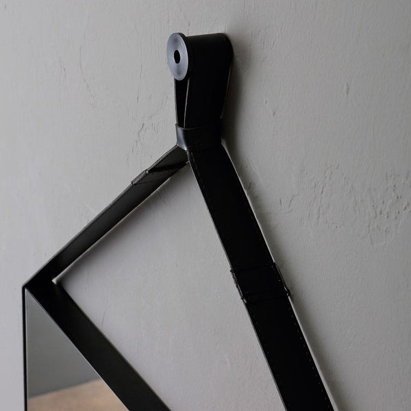 Schwarze Lederlasche zur Spiegelaufhängung mit runder Wandhalterung.