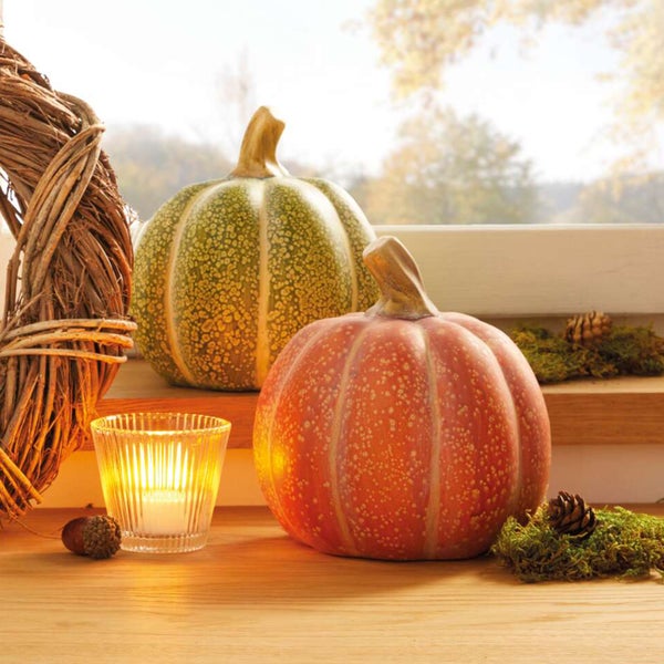 Dekorative Kürbisse mit Kerze und herbstlicher Dekoration auf einer Fensterbank