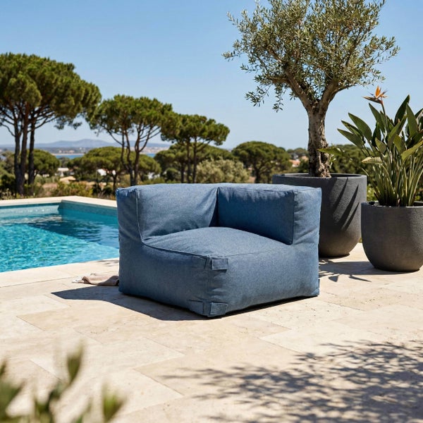 Blaues Outdoor-Loungesessel-Modul auf einer hellen Terrasse neben einem Pool mit Pflanzen in grauen Töpfen und Bäumen im Hintergrund.