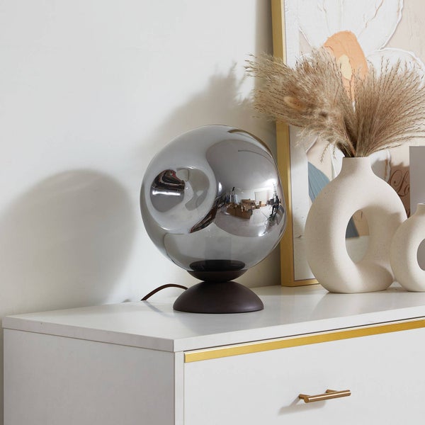 Dekorative Tischleuchte mit rundem Schirm auf einer weißen Kommode
