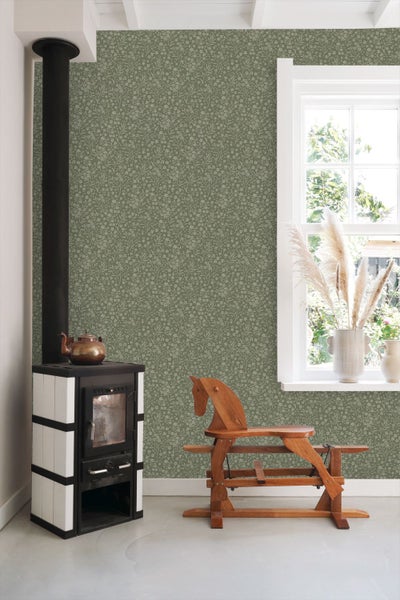 Vliestapete mit floralem Muster in einem hellen Raum mit Kaminofen und Holzschaukelpferd.