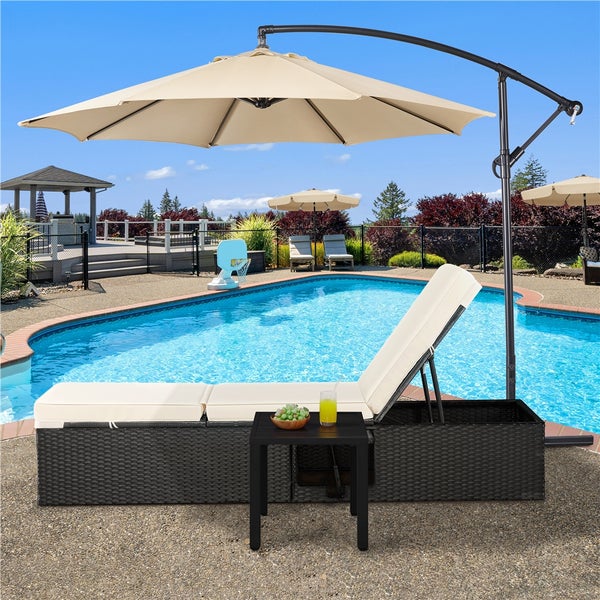 Sonnenliege aus Polyrattan mit beigefarbenem Polster und integriertem Ampelschirm am Pool mit Beistelltisch.