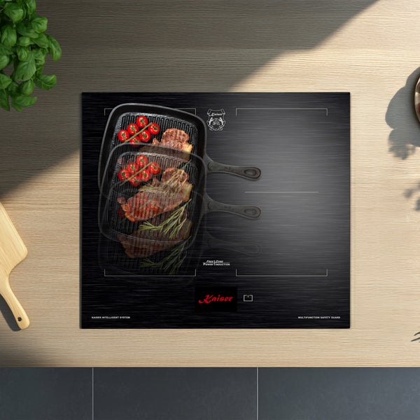 Kaiser Induktionskochfeld mit Free Zone Power Induction Technologie auf einer hölzernen Arbeitsplatte mit Grillpfanne und Steak.