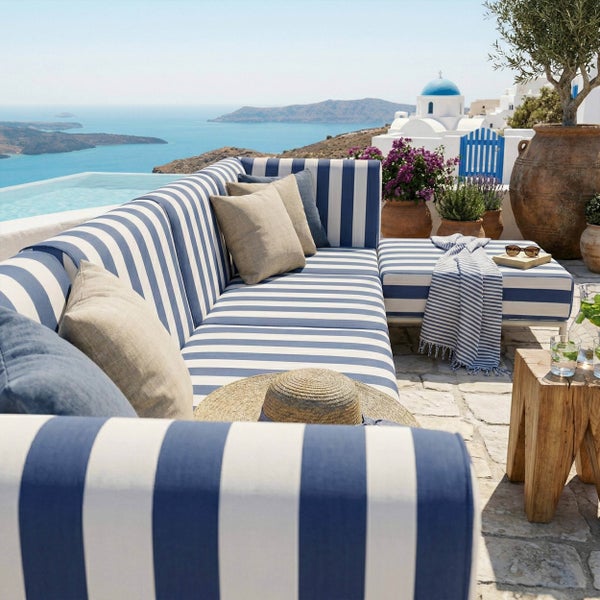 Gestreiftes Lounge-Ecksofa für den Außenbereich auf einer hellen Steinterrasse mit Meerblick, Beistelltisch aus Holz und Pflanzgefäßen aus Terrakotta.