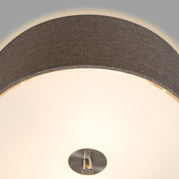 Nahaufnahme einer runden Deckenleuchte mit strukturiertem Stoffschirm und zentraler Metallhalterung von unten gesehen.