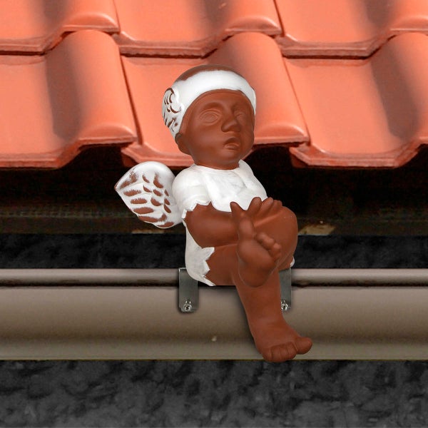 Dachrinnenfigur sitzender Engel aus Keramik an einer Dachrinne unter Dachziegeln.