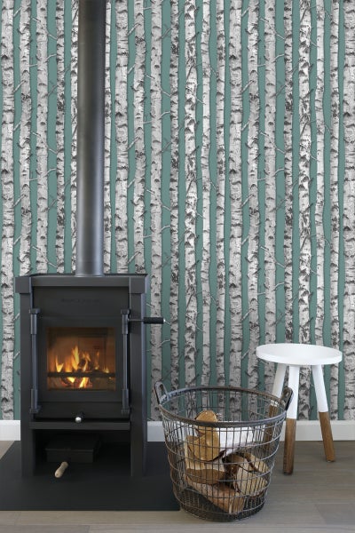 Wohnzimmer mit Kaminofen, Holzlagerkorb und Birkenwaldtapete