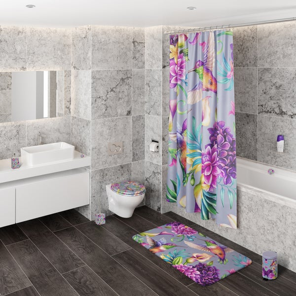 Modernes Badezimmer mit Wandfliesen in Marmoroptik, buntem Duschvorhang, Badematte und Toilettensitz mit Kolibri- und Blumenmotiv.