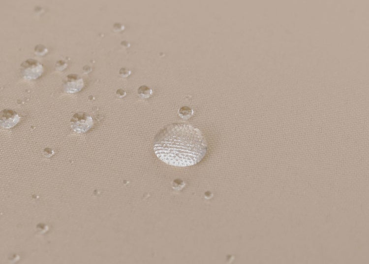 Detailansicht eines wasserabweisenden Gewebes mit Wassertropfen auf der strukturierten Oberfläche.