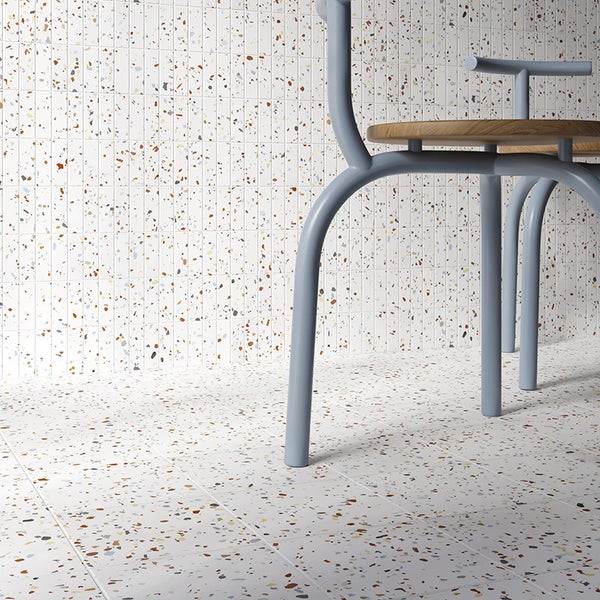 Wandfliesen im schmalen Format und quadratische Bodenfliesen in Terrazzo Optik mit buntem Granulat in einem modernen Wohnbereich.