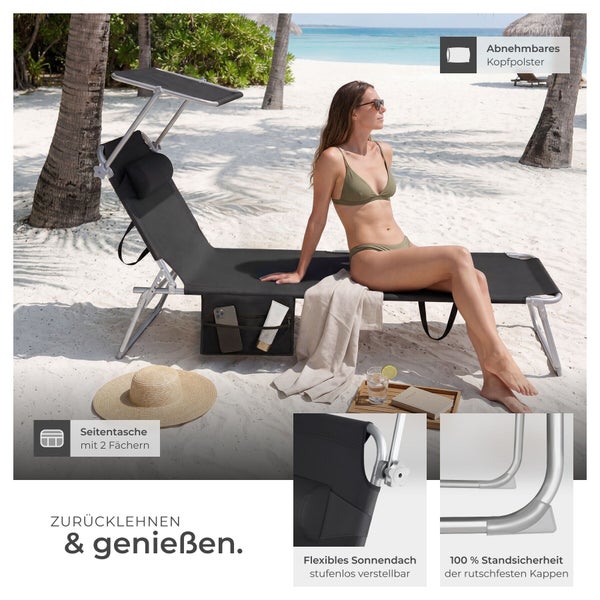Schwarze Gartenliege aus Aluminium mit Sonnendach, Seitentasche und Kopfpolster, auf der eine Frau an einem hellen Strand sitzt.