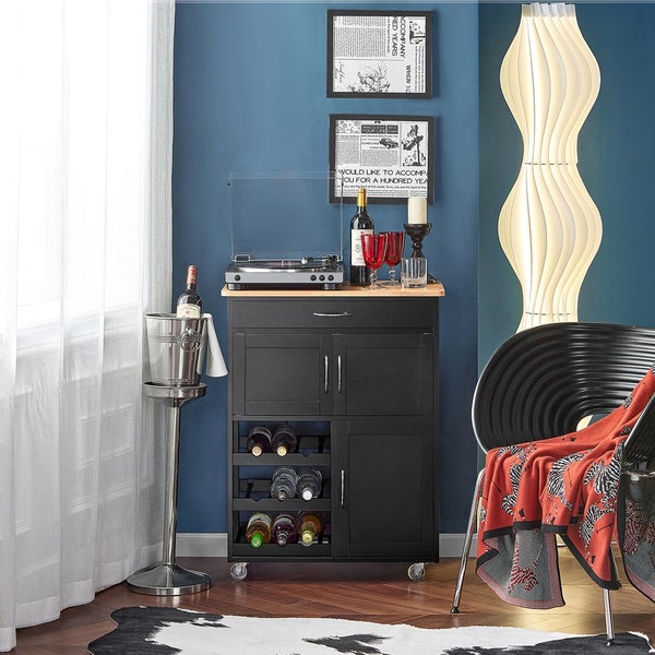 Szene mit einem Servierwagen mit Schublade, Schrank und Weinflaschenregal, einem Plattenspieler, Wein, Weingläsern und einer Stehlampe