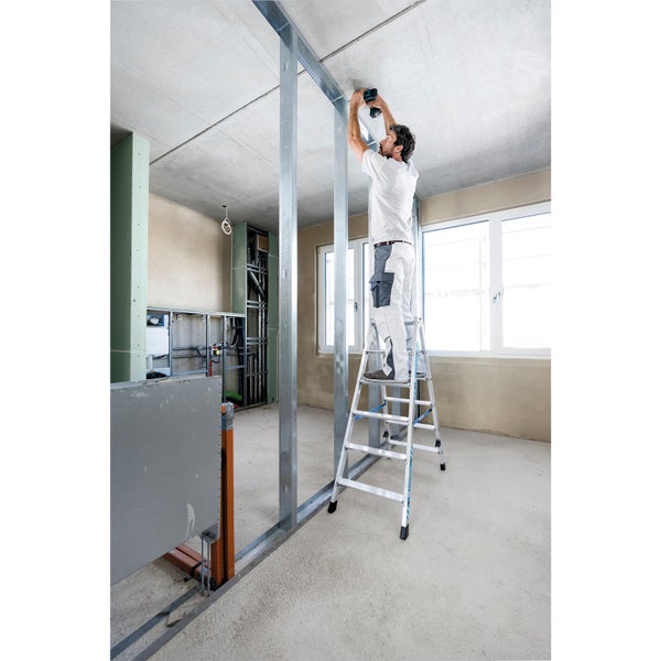 Mann auf Leiter befestigt Decke in einem Rohbau