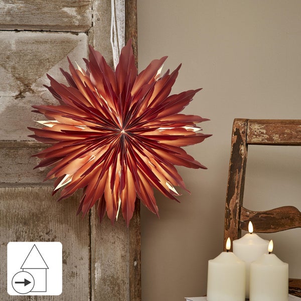 Dekorative Weihnachtsszene mit Papiersternen, Christbaumkugeln und Lichterketten auf einem Tisch