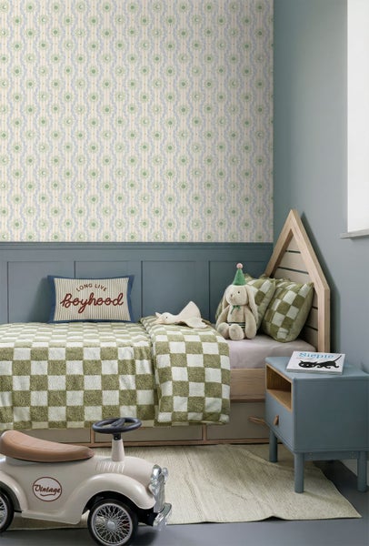 Helles Kinderzimmer mit Vliestapete mit Sonnen- und Mondmuster, einem Holzbett in Hausform und einer blau-grauen Wandvertäfelung.