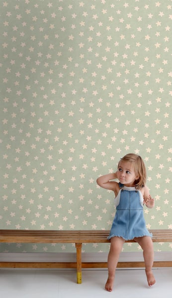 Mädchen sitzt vor einer Tapete mit Sternmuster