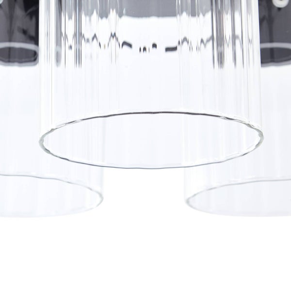 Nahaufnahme von drei zylindrischen, geriffelten Lampenschirmen aus klarem Glas.