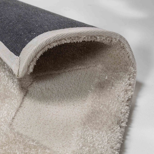 Nahaufnahme eines Hochflor-Teppichs mit weicher Textur, gewebter Rückseite und umkettelten Rändern.