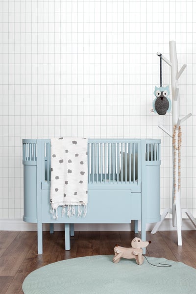 Helles Kinderzimmer mit Gitterbett, Spielzeug und Dekorationsartikeln für Babys