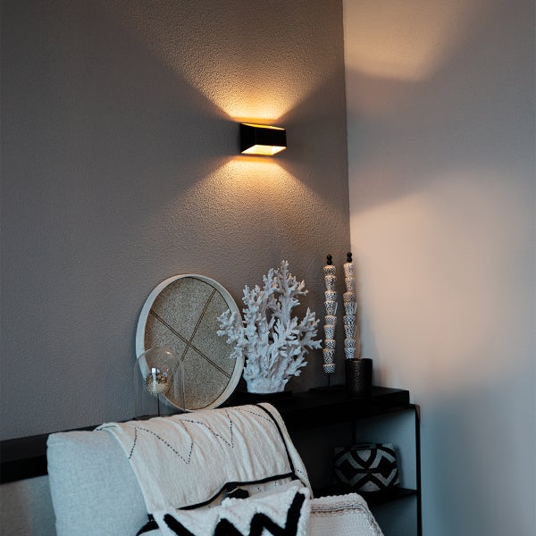 Wohnzimmer mit Wandleuchte und dekorativen Elementen auf einem Regal