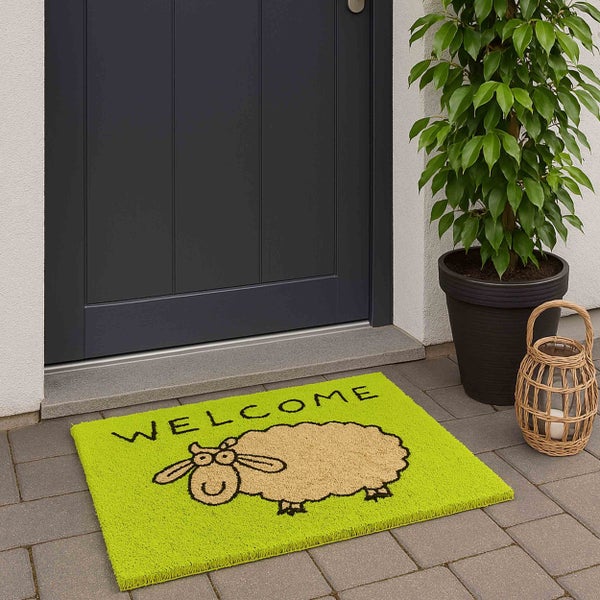 Fußmatte mit dem Schriftzug Willkommen und einem Schaf vor einer Haustür.