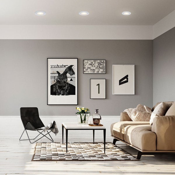 Wohnzimmer mit Deckenleuchten, Sofa, Sessel, Tisch und dekorativen Bildern an der Wand