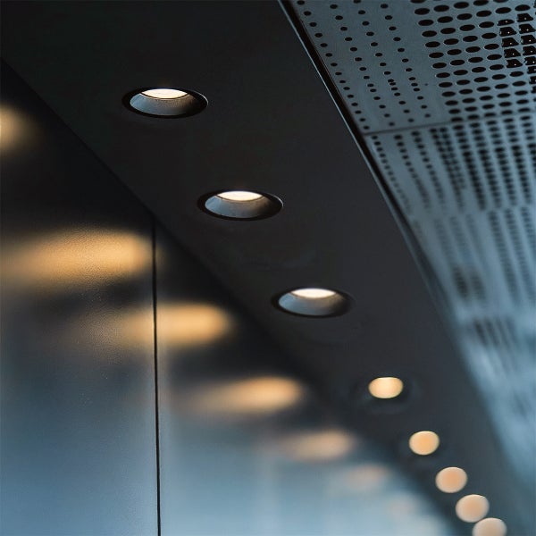 Einbau-LED-Strahler in einem Deckenpaneel, die warmes Akzentlicht mit Reflexionen an einer Wand erzeugen.