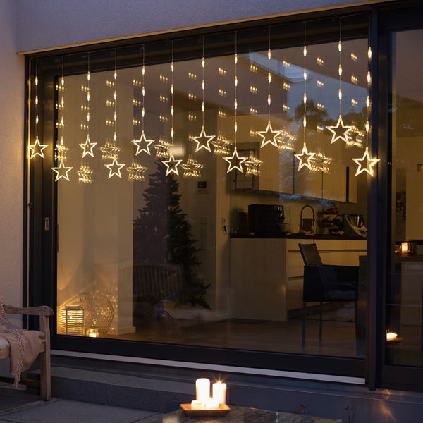 Dekorative Sternen-Lichterkette vor einem Fenster für festliche Beleuchtung.