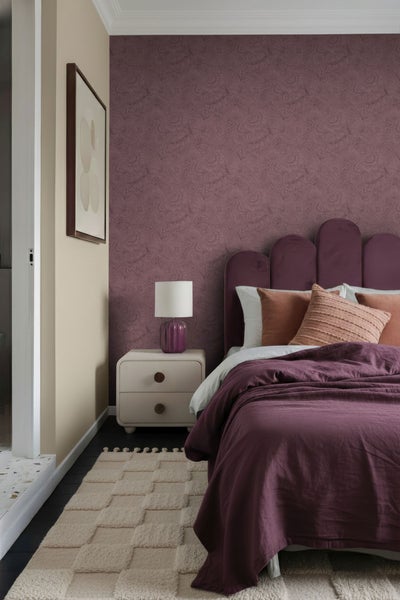 Gemütliches Schlafzimmer mit gemusterter Tapete, Bett, Nachttischlampe und Teppich