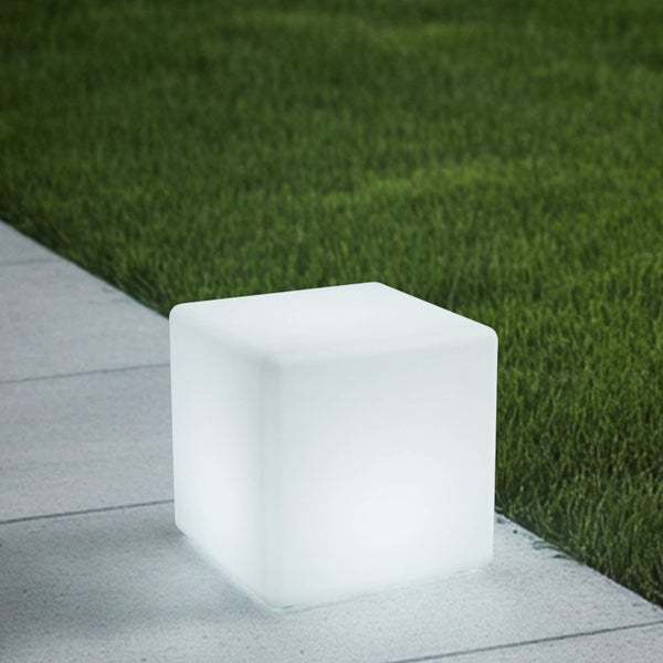 Leuchtender LED-Würfel auf einem Steinweg neben einer Rasenfläche als dekorative Gartenbeleuchtung.