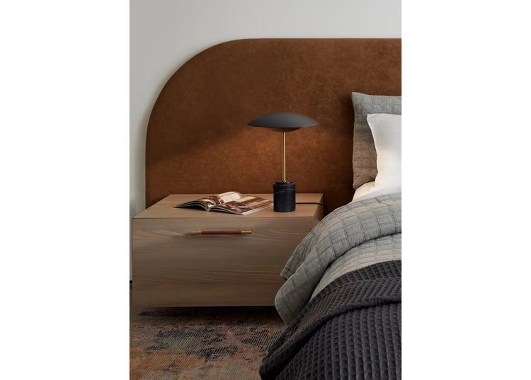 Moderne Schlafzimmereinrichtung mit Nachttisch aus Holz, Tischlampe und gepolstertem Kopfteil in einem behaglichen und stilvollen Ambiente.