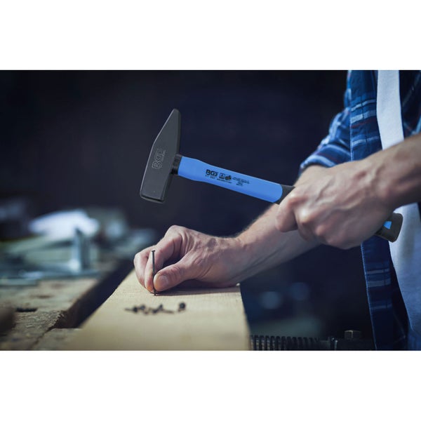 Ein Zimmermannshammer wird zum Einschlagen eines Nagels in ein Stück Holz verwendet