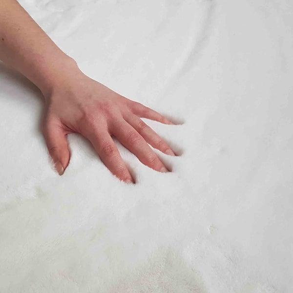 Eine Hand drückt auf eine weiche Matratze.