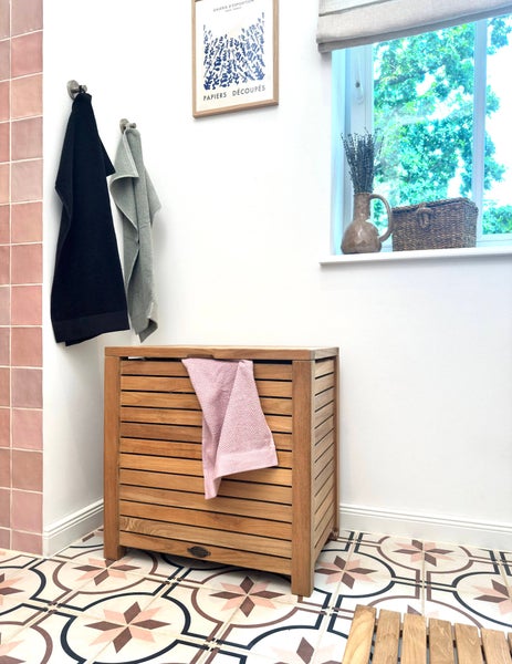 Helles Badezimmer mit Holzwäschekorb, Handtüchern und dekorativen Elementen