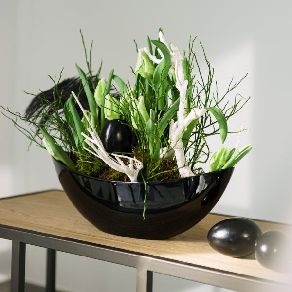 Dekoration mit Blumen, Ästen und Ostereiern in einer Schale