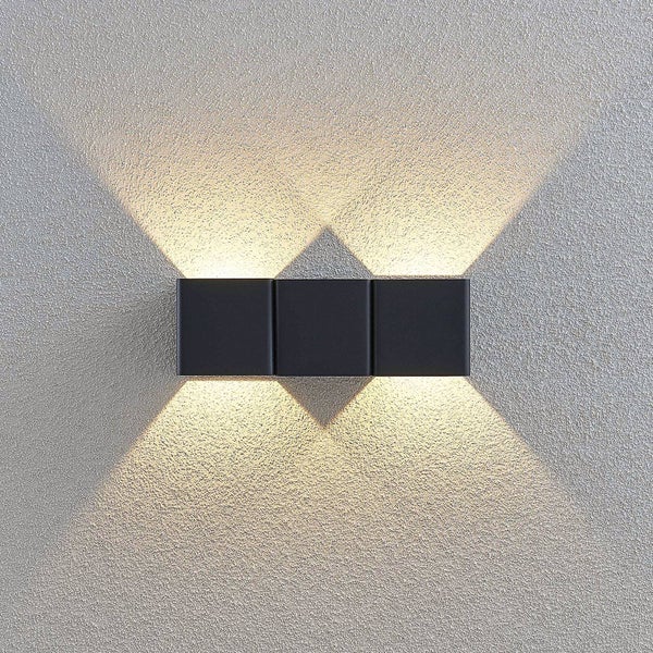 Schwarze dreiteilige Wandleuchte mit Up-and-Down-Lichteffekt an einer strukturierten Wand.
