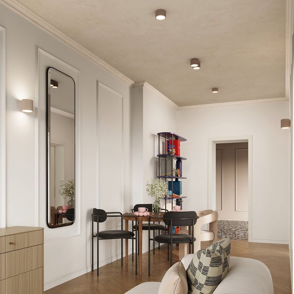 Heller Wohnbereich mit runden Decken- und Wandleuchten, einem großen Wandspiegel, Esstisch mit schwarzen Stühlen und Parkettboden.