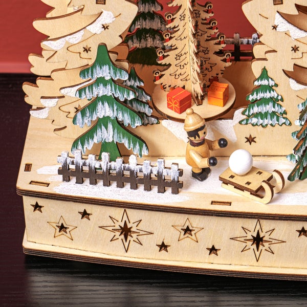 Weihnachtliche Winterlandschaft aus Holz mit Miniaturfigur, Schlitten, verschneiten Bäumen und dekorativen Sternen am Sockel.