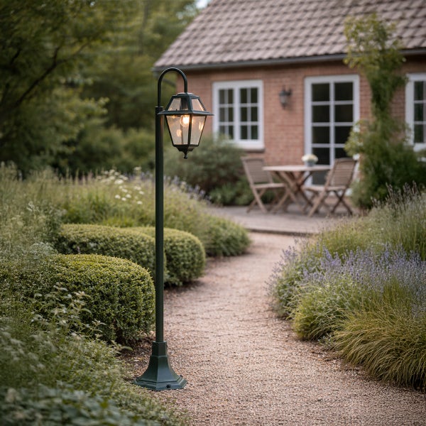 Klassische Wegeleuchte im Garten an einem geschotterten Pfad vor einem Backsteinhaus