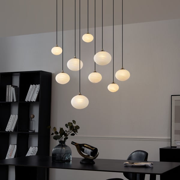 Moderne Esstischszene mit kugelförmiger Pendelleuchte über einem schwarzen Tisch