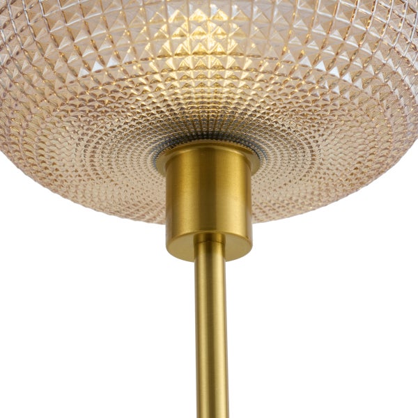 Detailansicht einer Lampe mit strukturiertem Glasschirm und goldfarbener Metallstange.