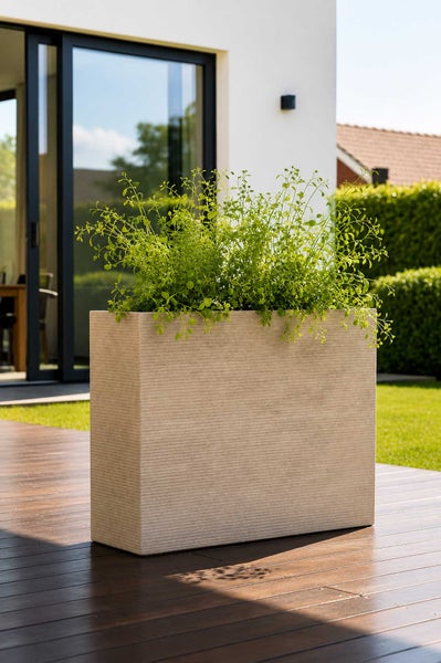 Rechteckiger Pflanzkasten mit feiner Rillenstruktur auf einer Holzterrasse im Garten.